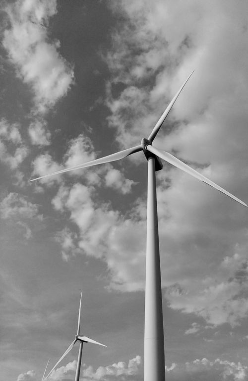 Free Black and white image of wind turbines harnessing renewable energy beneath dramatic cloud formations. Stock Photo