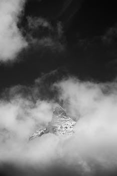 A striking black and white photo captures the Matterhorn peak enveloped in clouds, revealing its majestic form.
