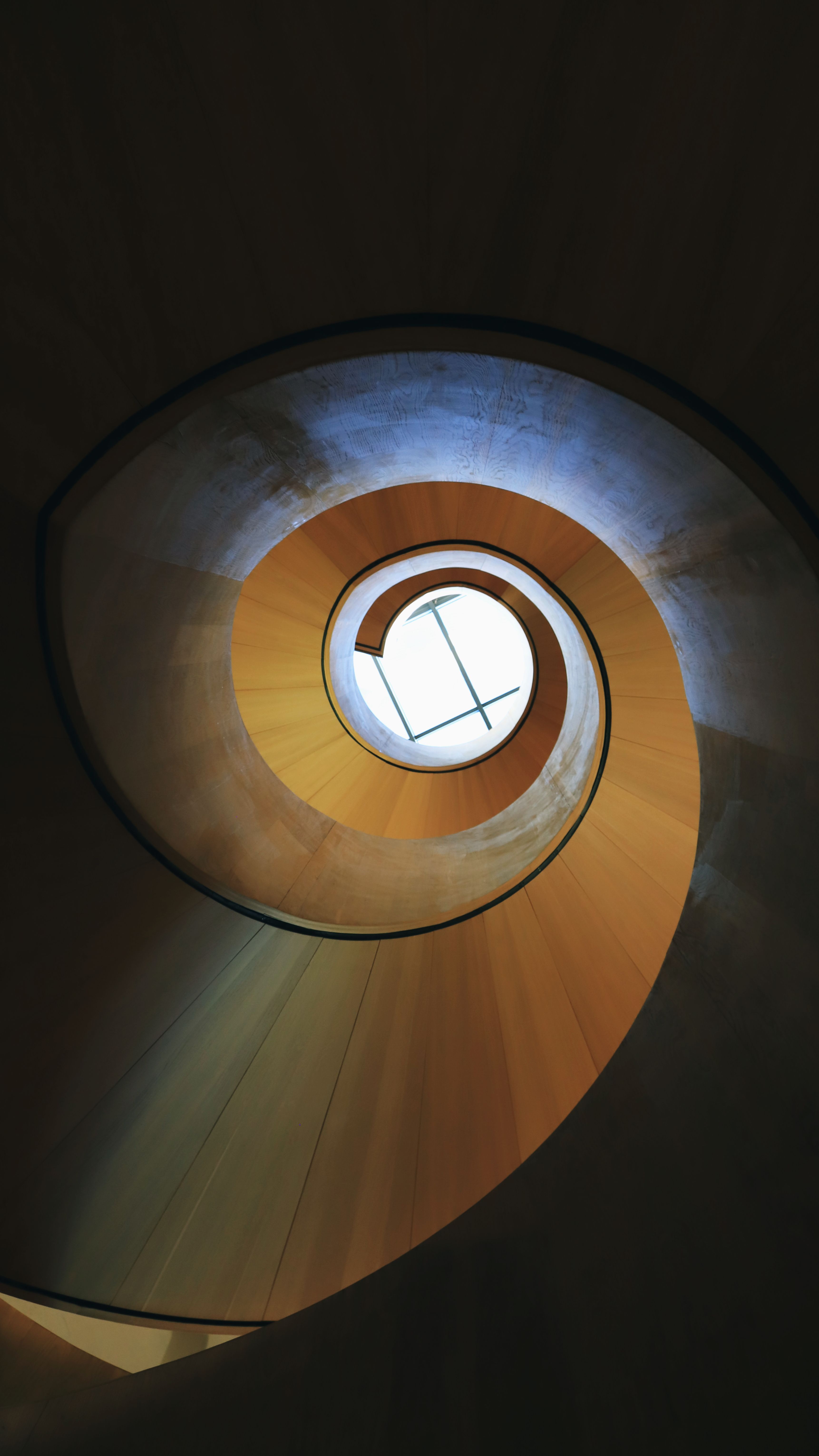 A captivating upward view of a spiral staircase leading to a circular skylight.