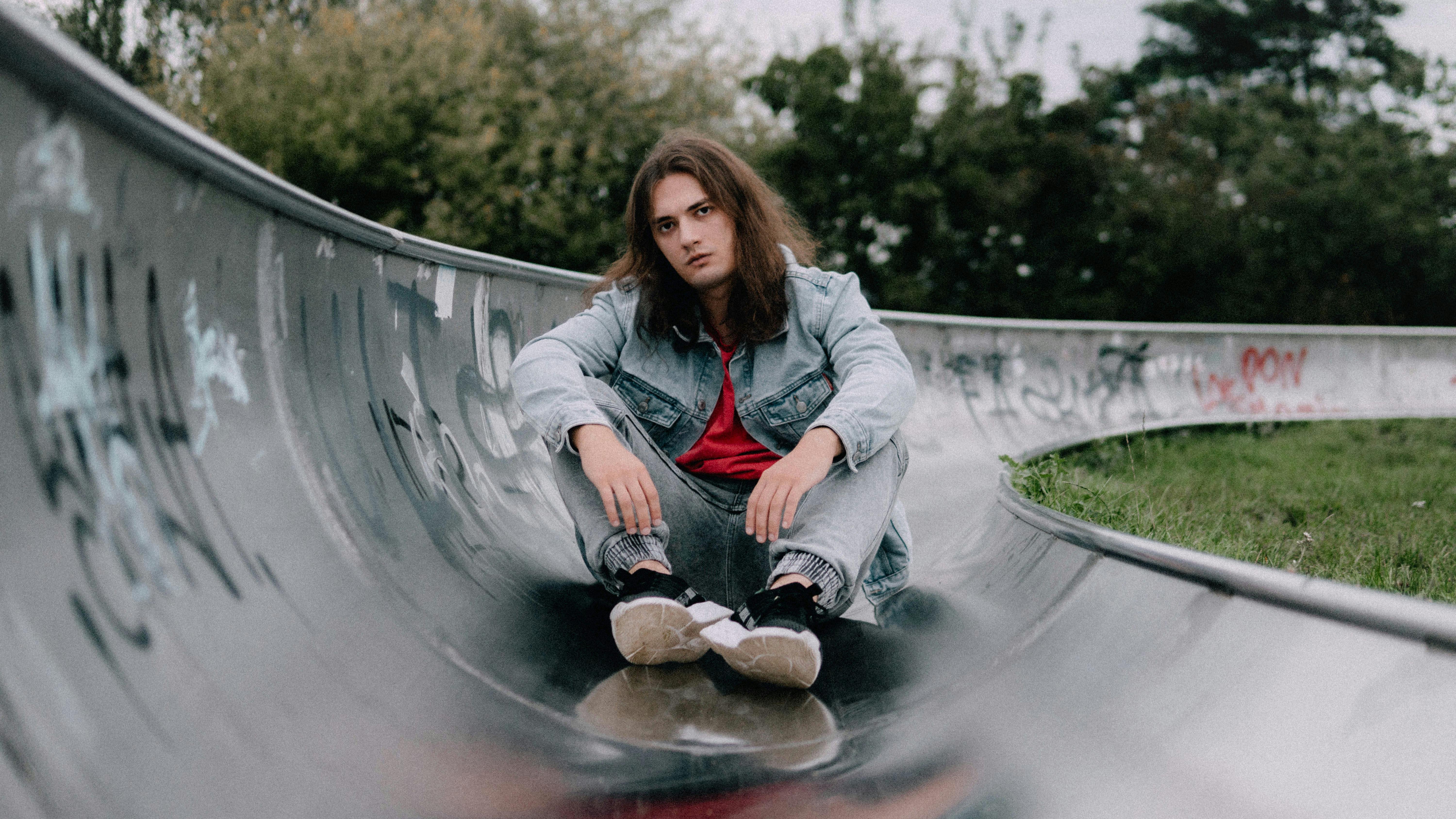 Gratis Ung voksen sitter på en graffiti-skaterampe i Łódź, Polen, og utstråler en avslappet og moderne atmosfære. Arkivbilde