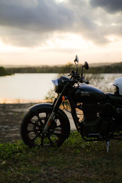 Free A classic motorcycle parked by a lake at twilight, exuding adventure. Stock Photo