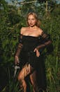 一个女人穿着黑色礼服，站在郁郁葱葱的绿色背景前，头饰精美