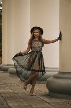 一位穿着优雅连衣裙的女士在白色柱子旁摆出姿势，展示时尚和风格