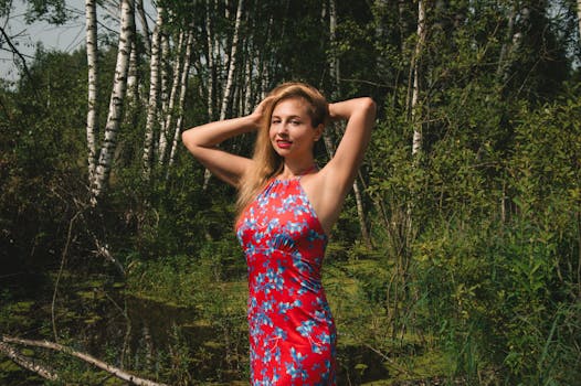 一名身穿红色花卉连衣裙的女子在郁郁葱葱的森林中自信地摆姿势
