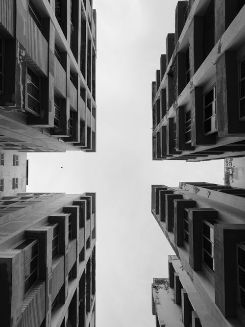 Free Black and white photo of tall buildings with a skyward view creating a dramatic urban scene. Stock Photo