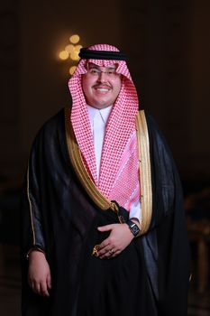 Middle-Eastern man in traditional clothing with a friendly smile indoors.