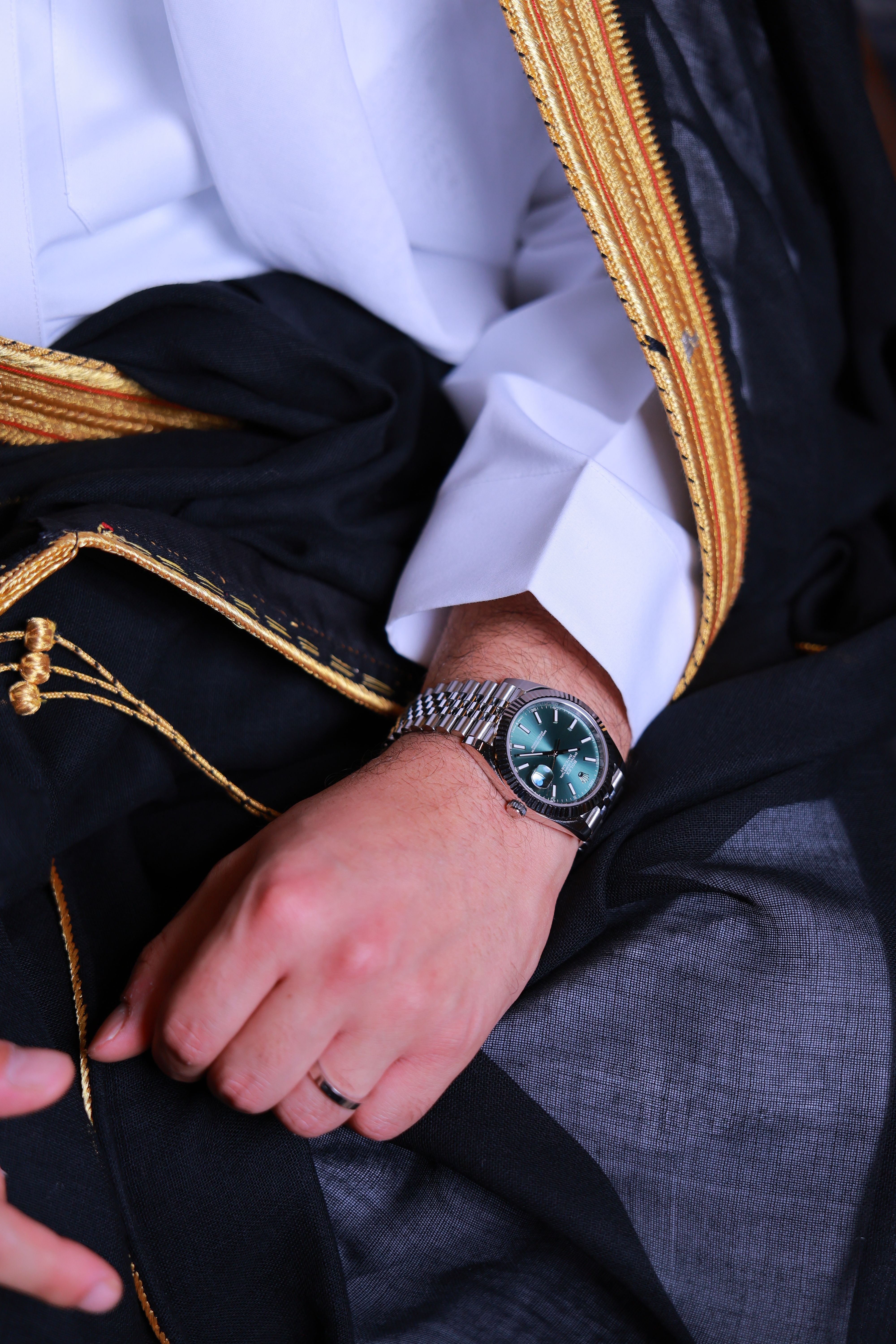 Close-up of a wristwatch on a man wearing traditional attire, showcasing elegance and style.