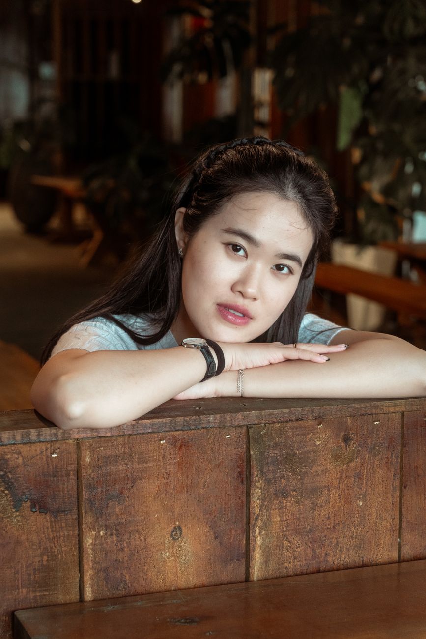 Charming portrait of a young woman relaxing in a warm, cozy cafe interior.