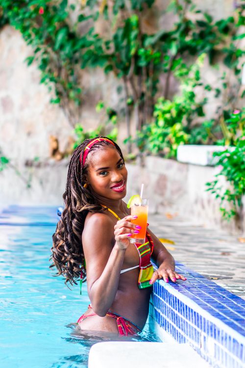 Free A joyful woman in a pool, holding a vibrant tropical cocktail, capturing the essence of summer relaxation. Stock Photo
