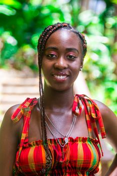 A joyful portrait of a woman in a bright dress with braided hair outdoors