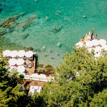 充满活力的海滩场景在空中拍摄中得以呈现，游泳者和日光浴者在清澈的蓝色大海和晴朗天气中尽情享受