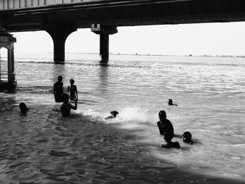 Free A black and white photo of children enjoying swimming under a bridge. Stock Photo
