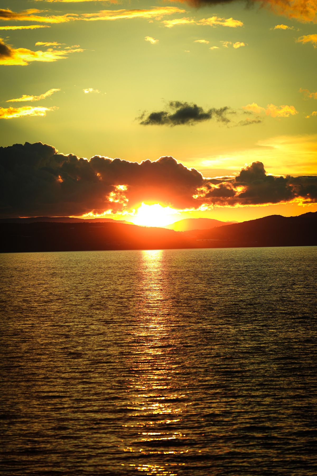 A sunset over the water with clouds in the sky · Free Stock Photo