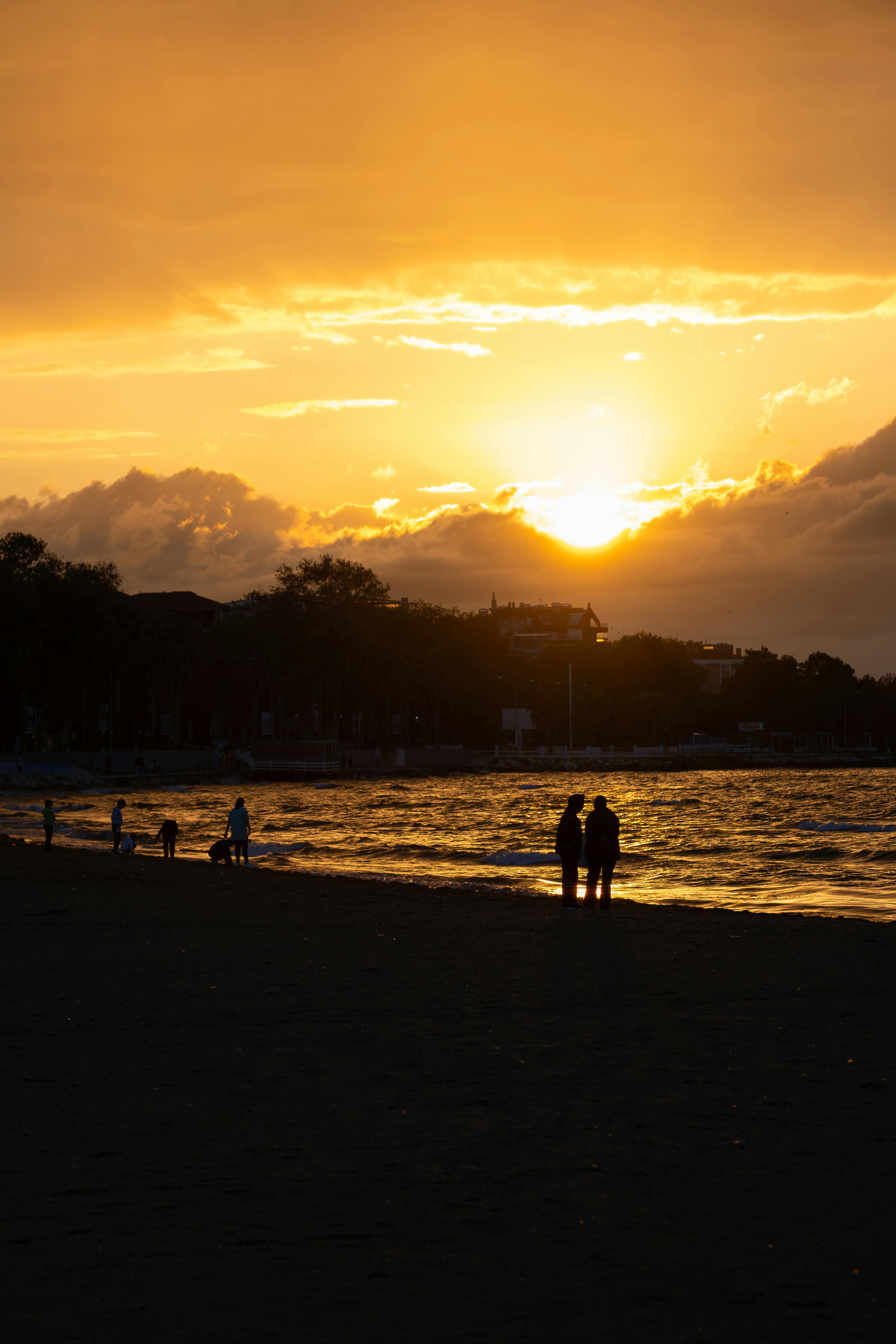 在充满活力的日落时分，亚洛瓦海滩上人们的剪影被捕捉到，呈现出宁静而浪漫的画面