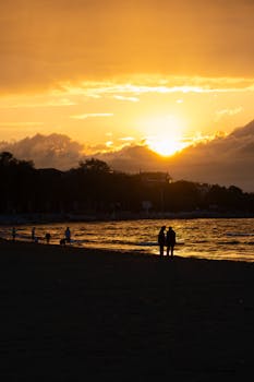 在充满活力的日落时分，亚洛瓦海滩上人们的剪影被捕捉到，呈现出宁静而浪漫的画面