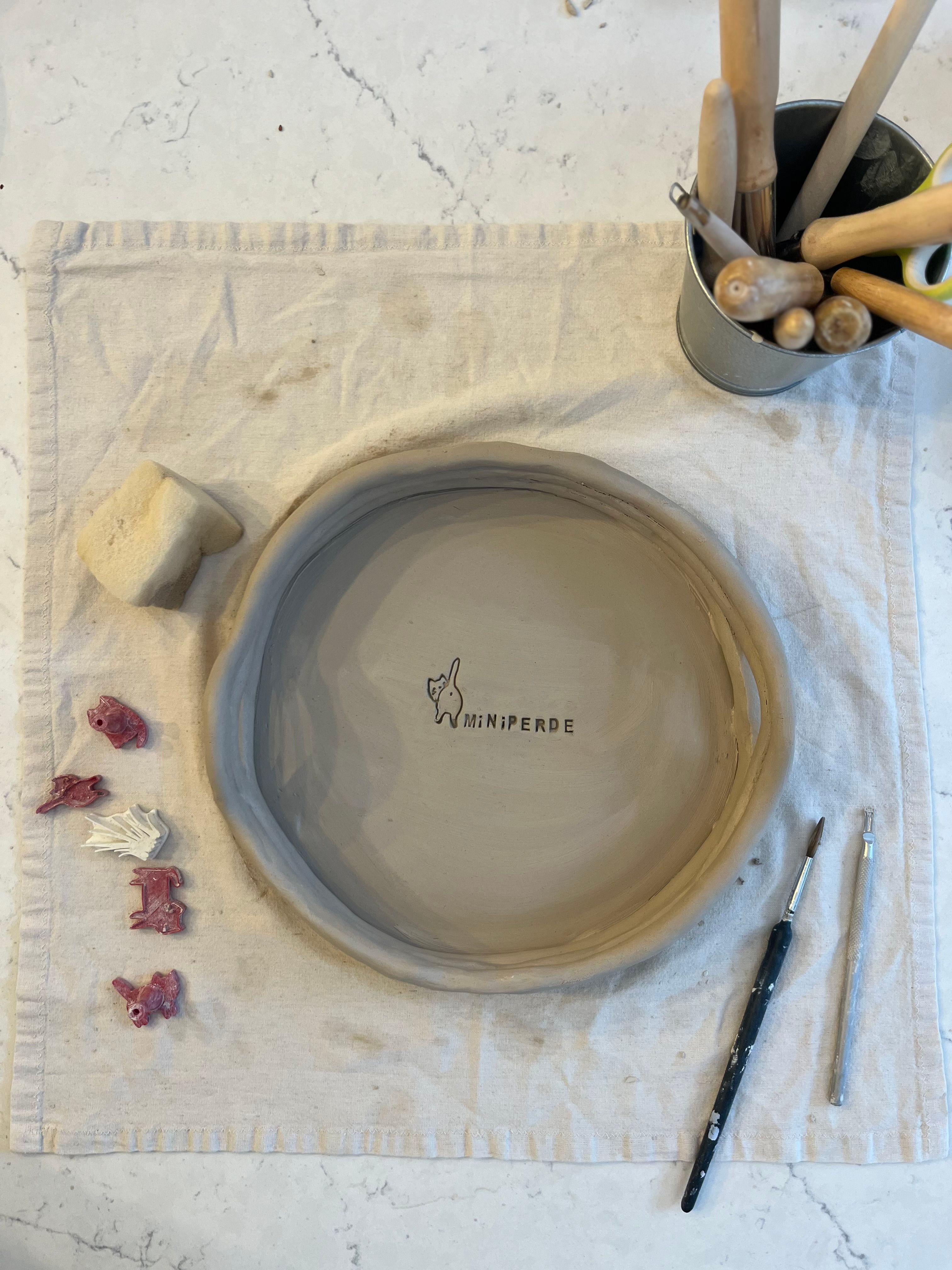 Beautiful clay bowl in progress with tools and materials on a pottery worktable.