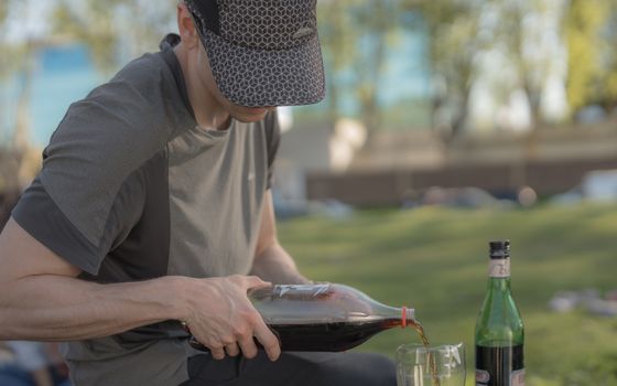 A man in a cap pouring traditional mate drink outdoors in Buenos Aires, Argentina, in a relaxed setting.