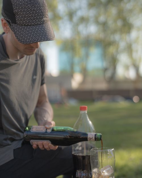 Free A man in a cap pouring a beverage outdoors in a park setting on a sunny day in Buenos Aires. Stock Photo