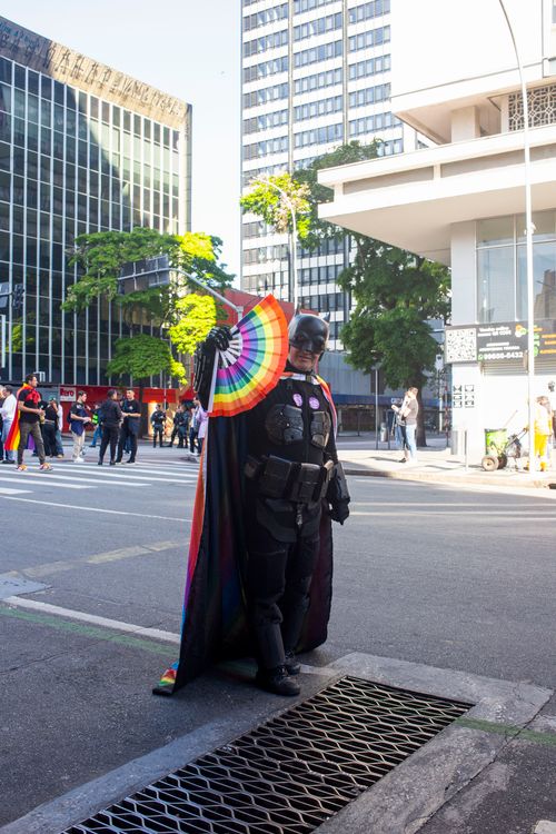 Free Vibrant scene from a Pride parade in Curitiba featuring a participant dressed in a superhero costume with a rainbow fan. Stock Photo