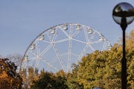 在晴朗的天空下，摩天轮透过色彩缤纷的秋季树木窥视