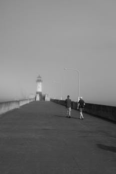 在德卢斯的一个雾蒙蒙的码头上，两个人走向灯塔，这是一幅忧郁的经典场景