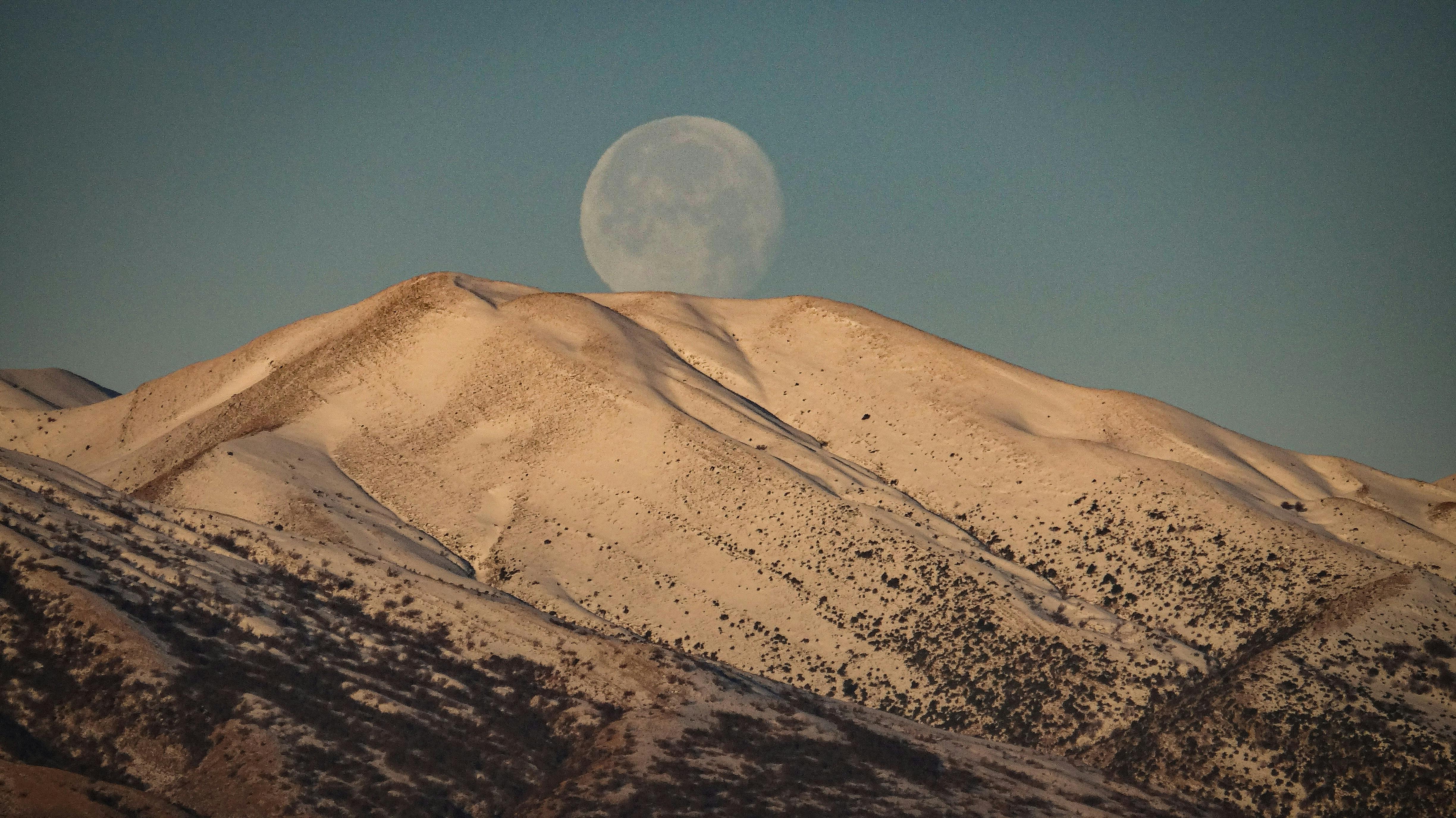 迷人的月色在白雪覆盖的山脉上，映照出宁静的冬季景观