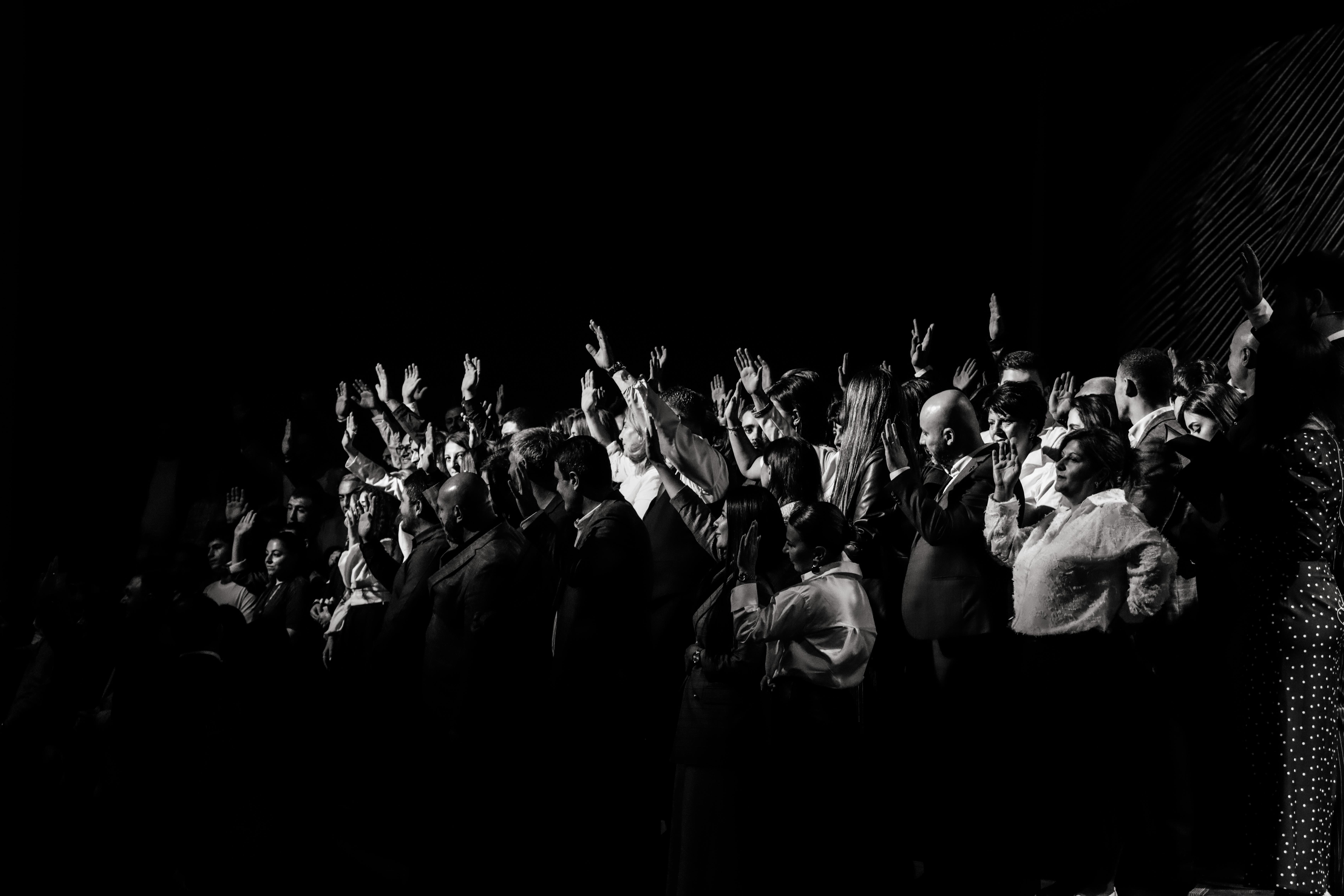 Free A dynamic black and white scene of a crowded group raising hands in unison at an event. Stock Photo