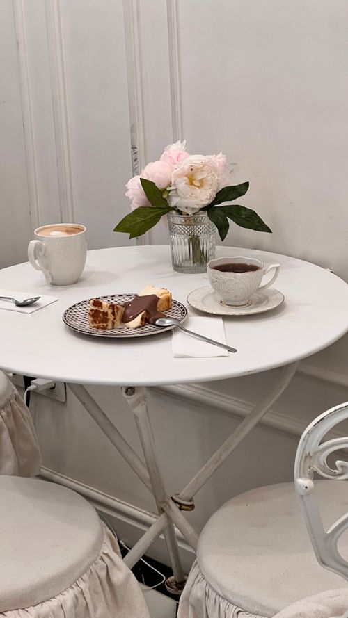 Free Cozy cafe setting with tea, coffee, pastry, and flowers on a round table. Stock Photo