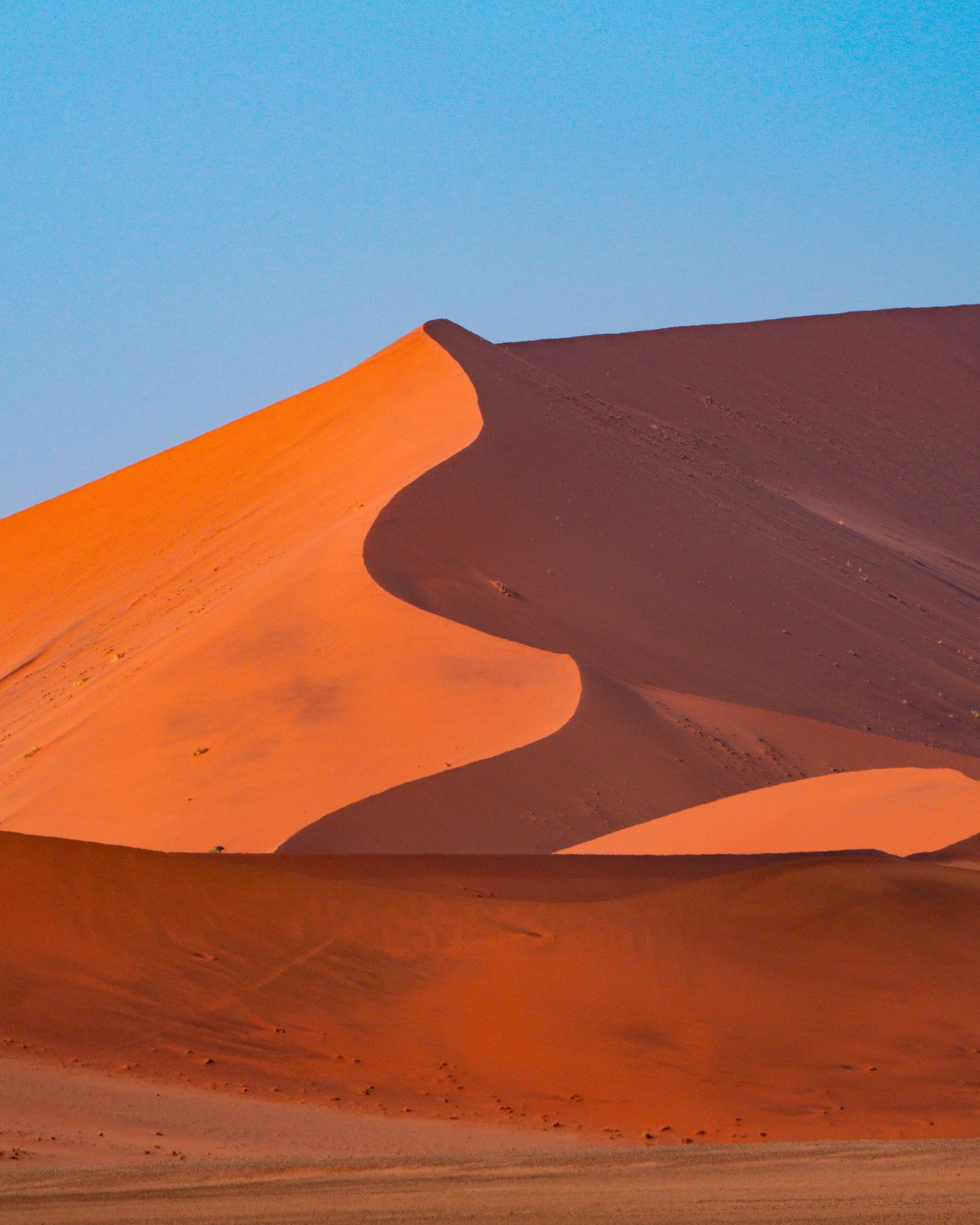 Towering red sand dunes under a clear blue sky at Sossusvlei in the Namib Desert, Namibia