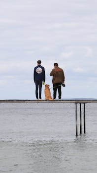 两名男子和一只狗在丹麦奥胡斯的码头上欣赏宁静的景色
