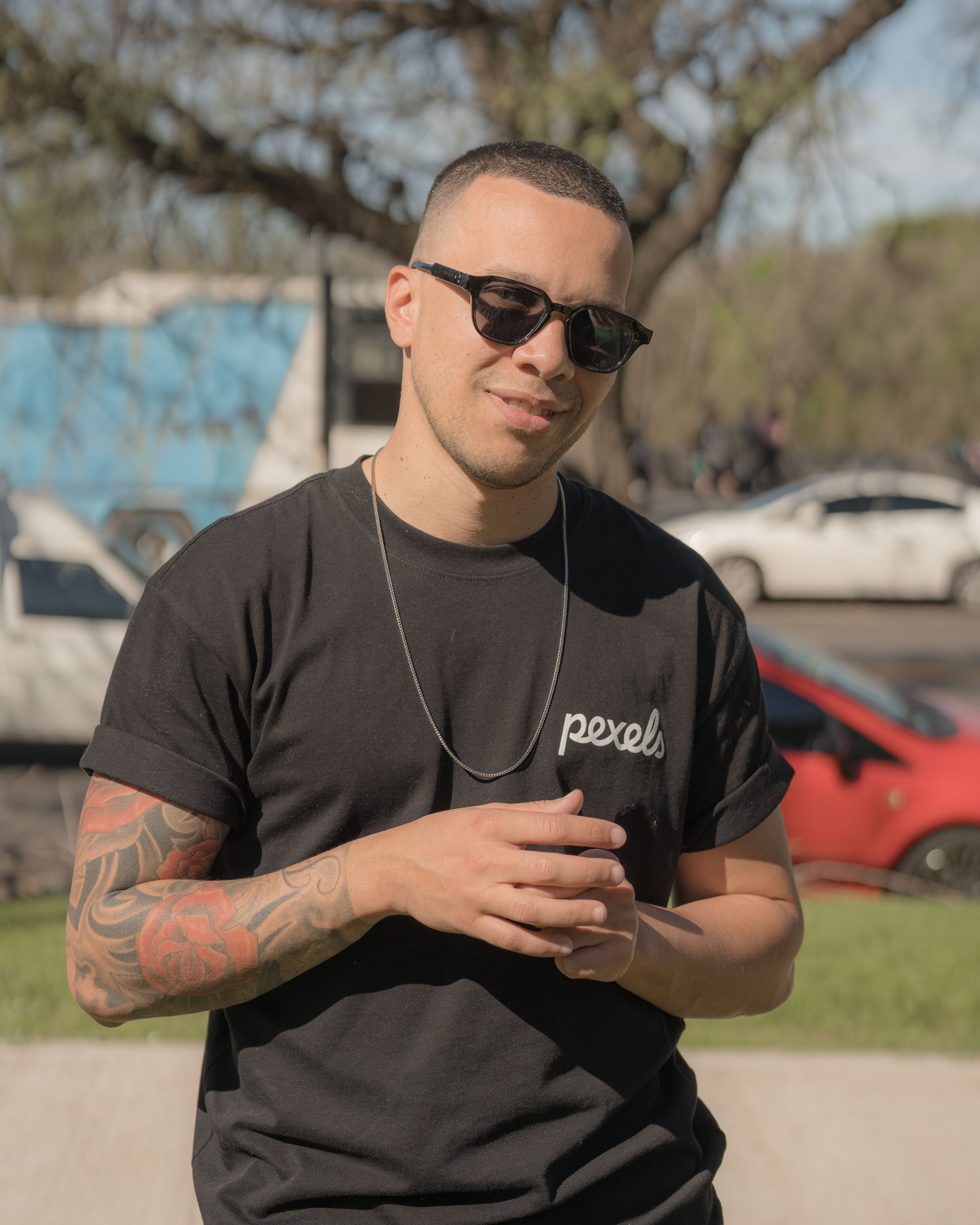Man in sunglasses and tattoo in Buenos Aires, Argentina, enjoying a sunny day outdoors.