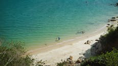 宁静的海滩上，伞下的孩子和人欢快地在水中玩耍