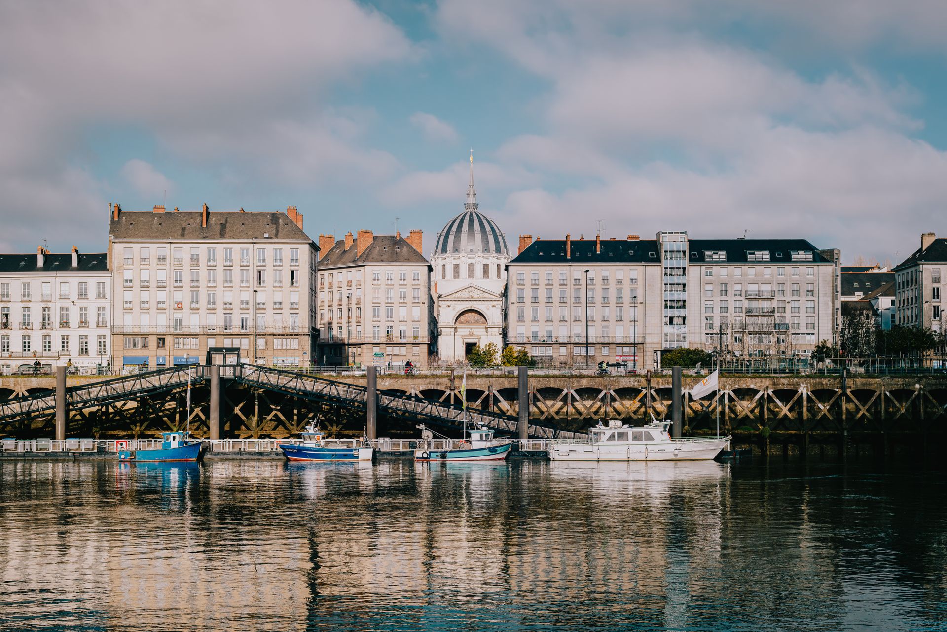 Architecture of Nantes with reflections on the Loire River under a bright sky.