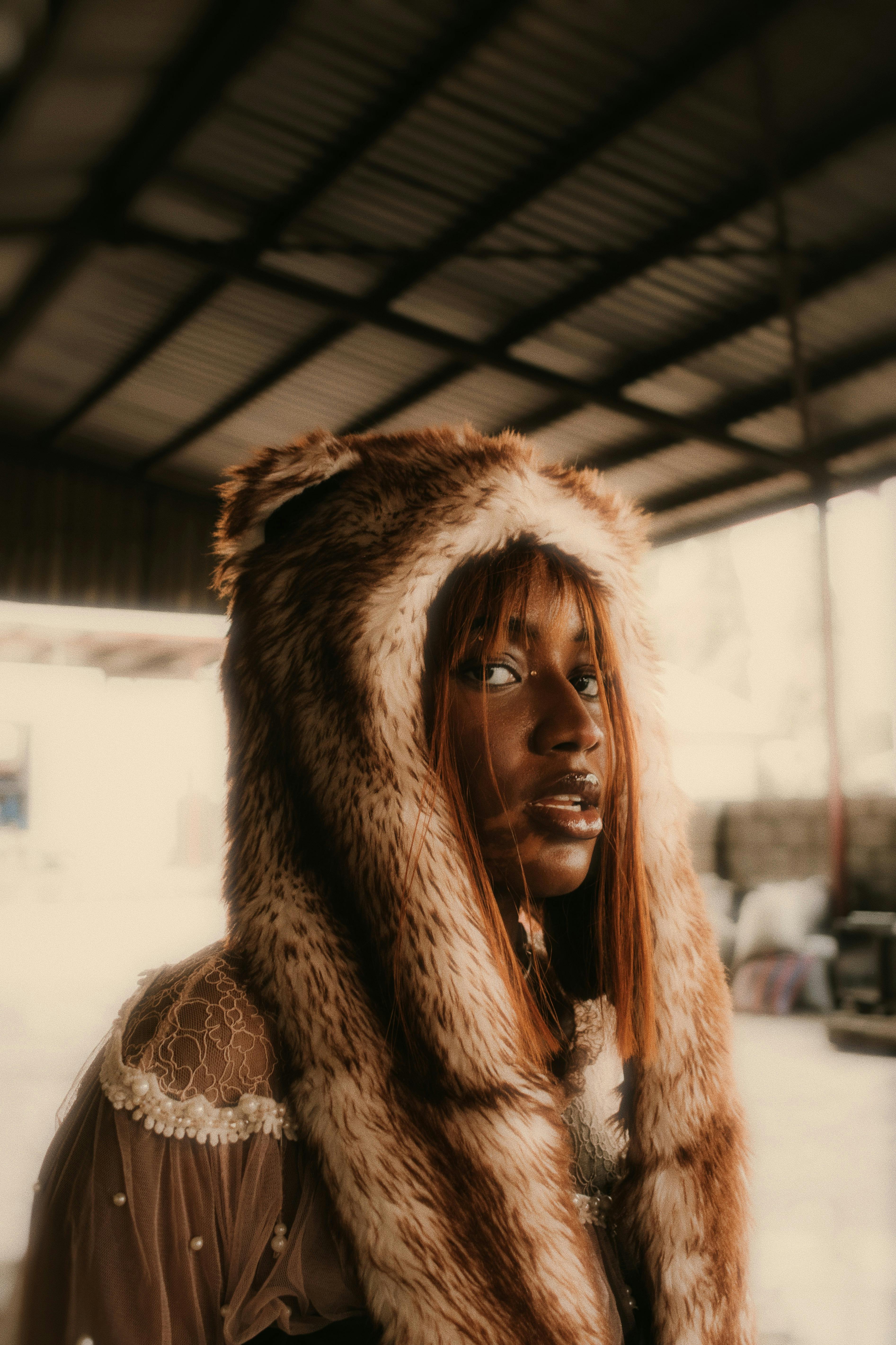 Stylish portrait of a woman wearing a faux fur hat in an industrial setting, Abuja.