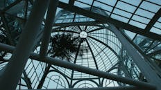 低角度视角下的现代玻璃圆顶结构，带有钢梁，展现了复杂的建筑设计