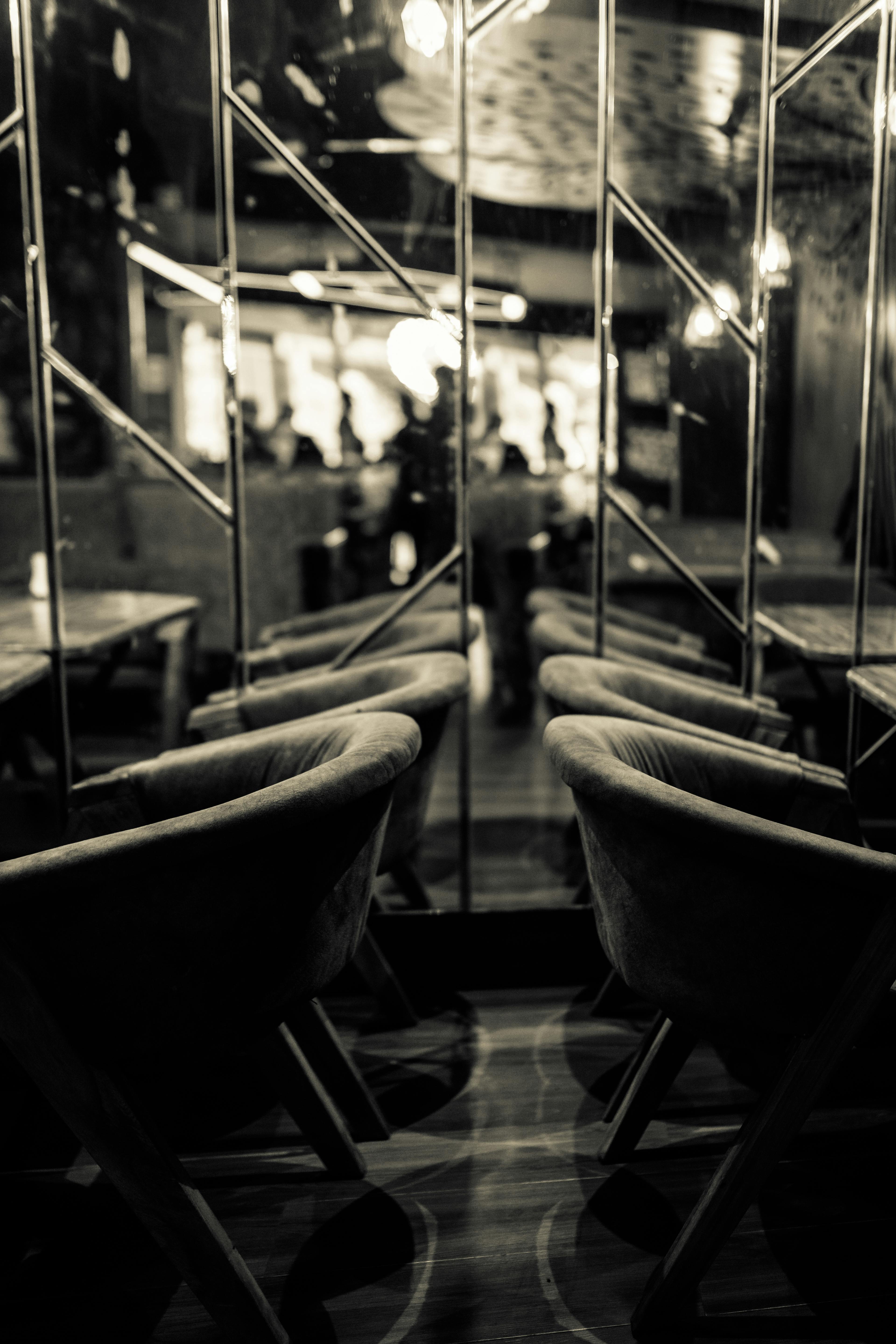 Ücretsiz Orta yüzyıl modern tasarımını ve aynalı yansımaları yansıtan, sıcak bir akşam ambiyansı yaratan, rahat ve loş ışıklı bir kafe iç mekanı. Stok Fotoğraflar