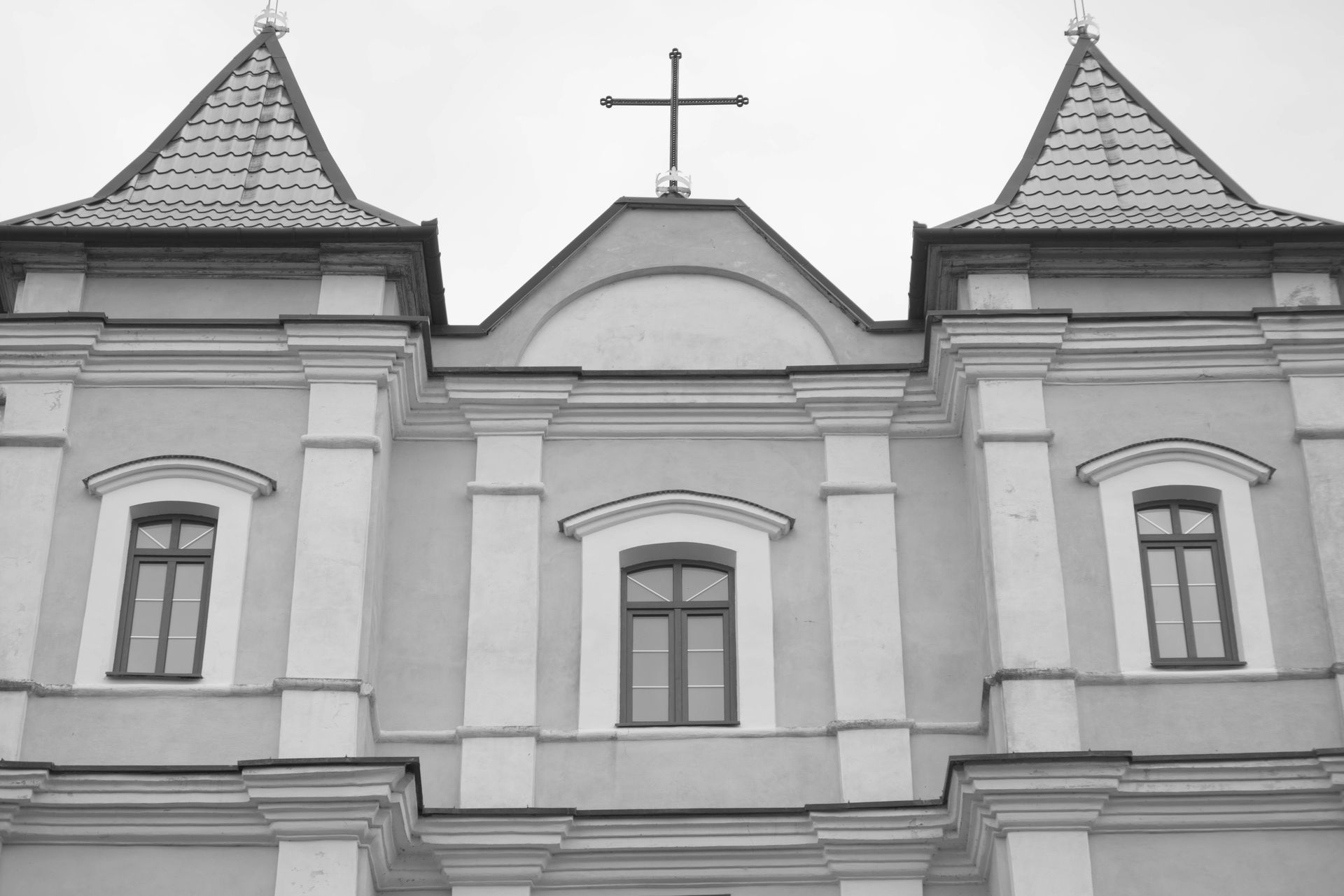 Black and white photo of a historic church facade with a prominent cross.