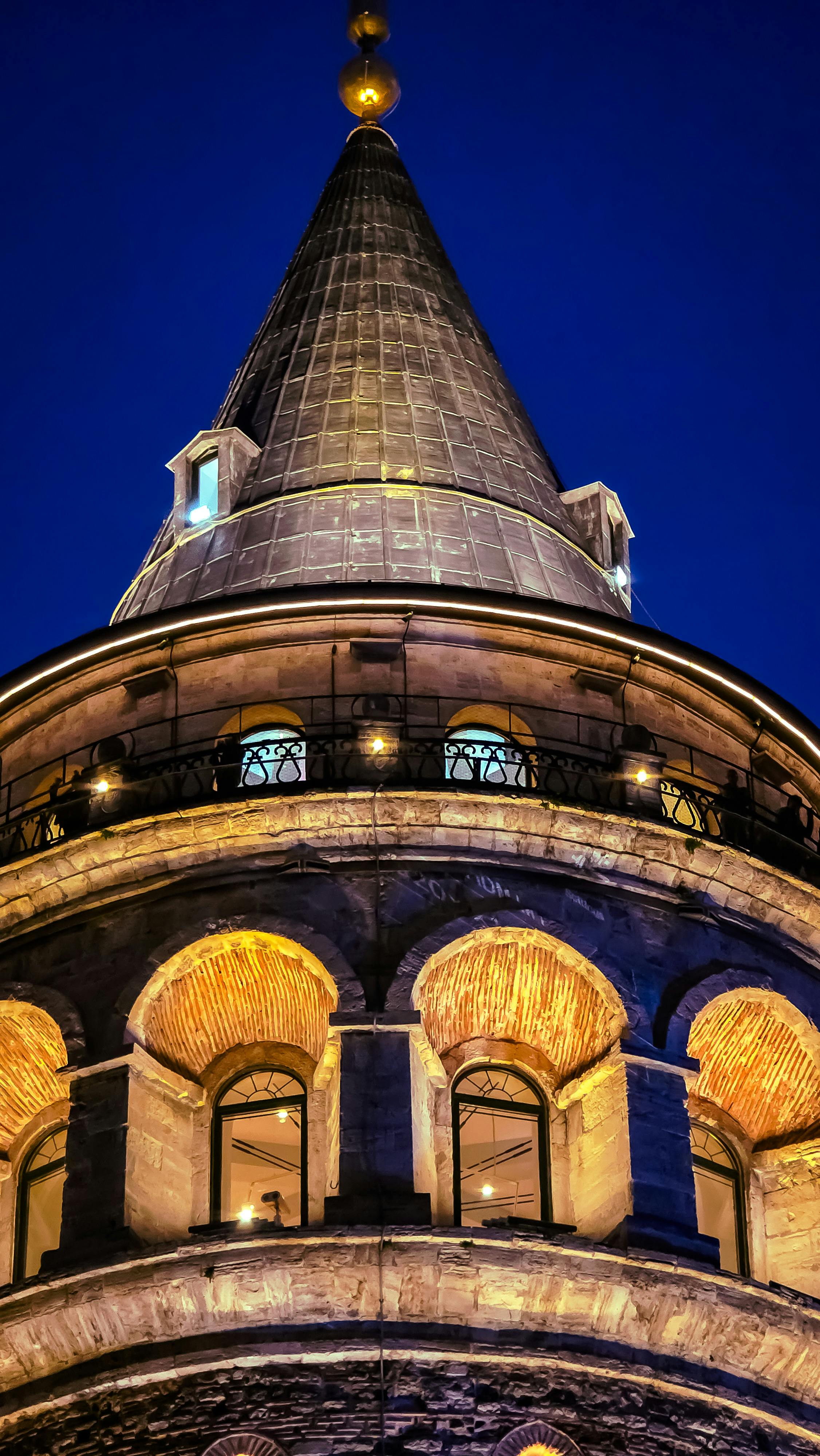 在伊斯坦布尔，历史悠久的加拉塔大厦在迷人的夜色中熠熠生辉，其灯光在蓝天的映衬下显得格外优美