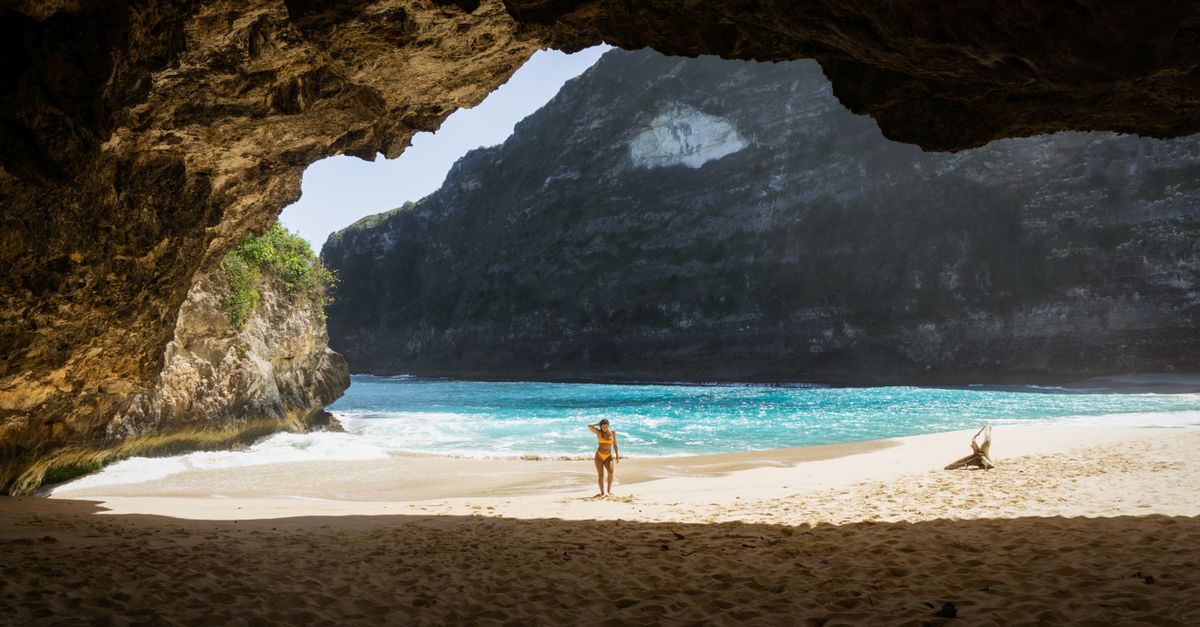 Remote white sand beach in Bali with turquoise water and limestone cliffs