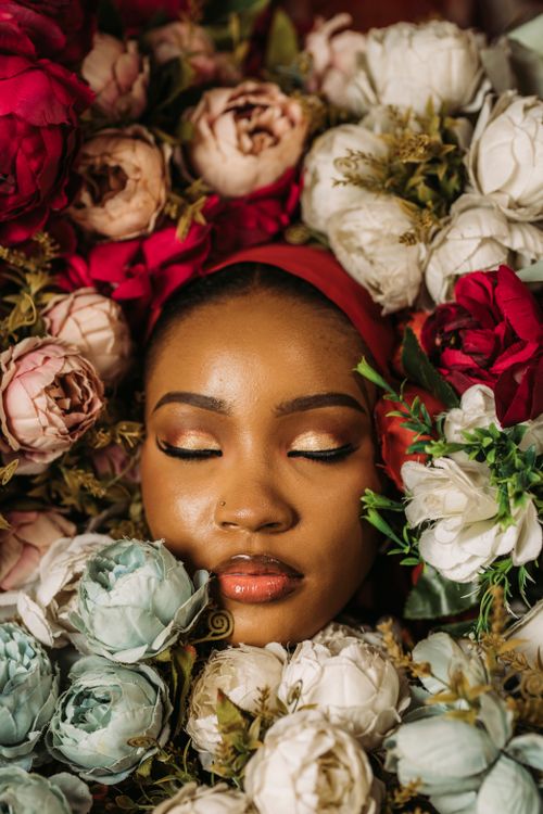 Free Portrait of a woman surrounded by diverse colorful flowers, conveying serenity. Stock Photo
