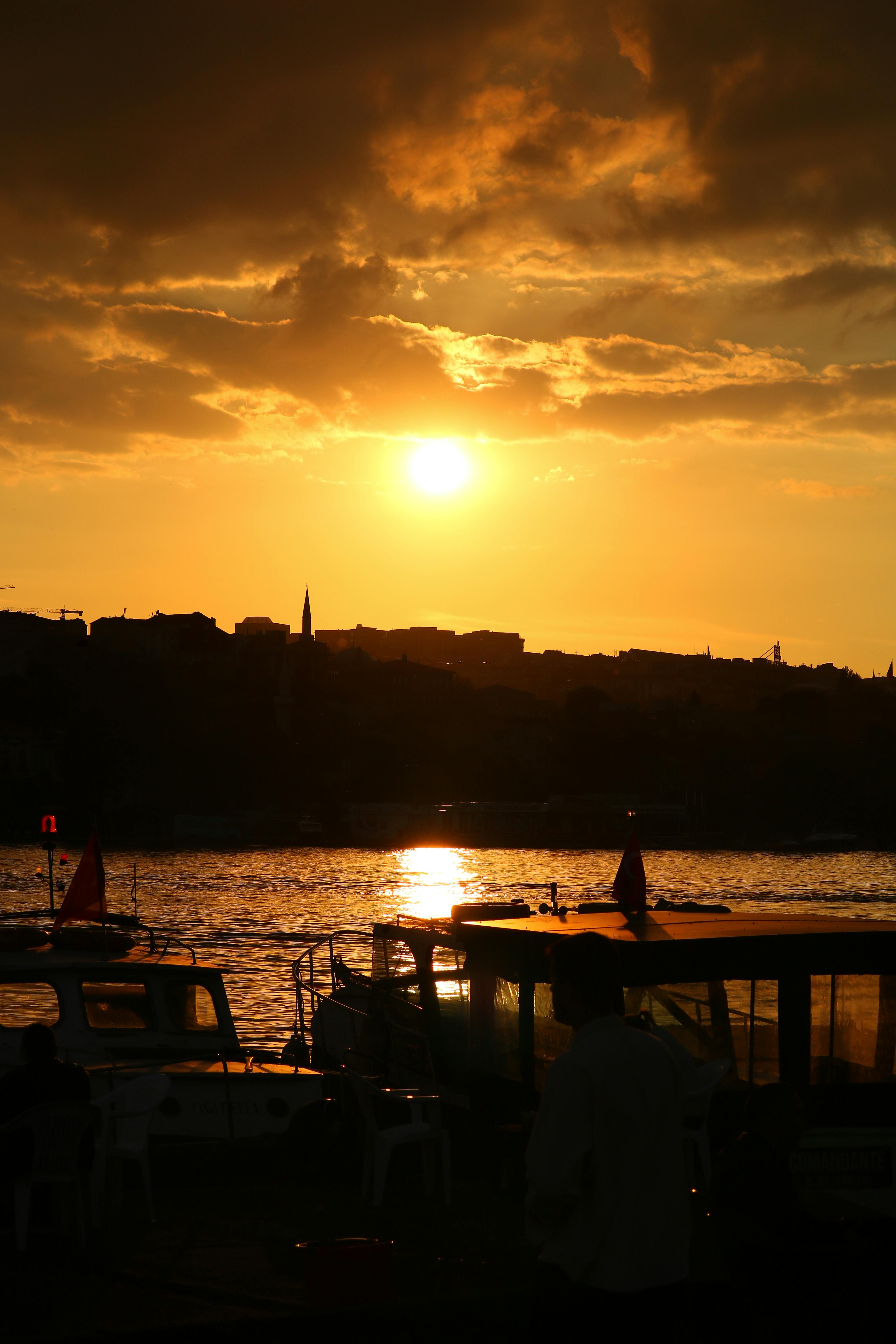 在伊斯坦布尔海滨，戏剧性的日落映照在剪影和灿烂的金色天空中