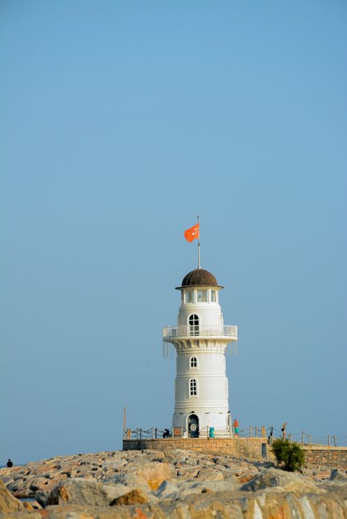 Free Lighthouse with Turkish flag under a clear blue sky on rocky terrain. Stock Photo