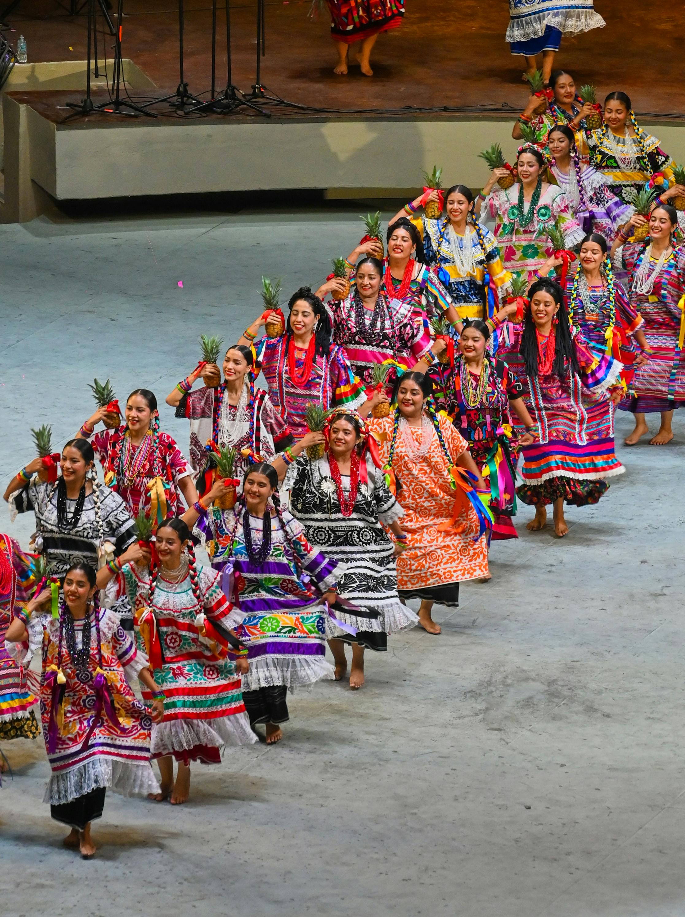 Ücretsiz Geleneksel kıyafetleriyle renkli kadınlar, kültürel miraslarını sergileyen tiyatro ortamında kültürel bir dans sergiliyorlar. Stok Fotoğraflar