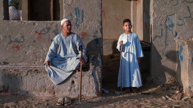 A father and son in traditional galabeya enjoy the afternoon sun in Giza, Egypt.