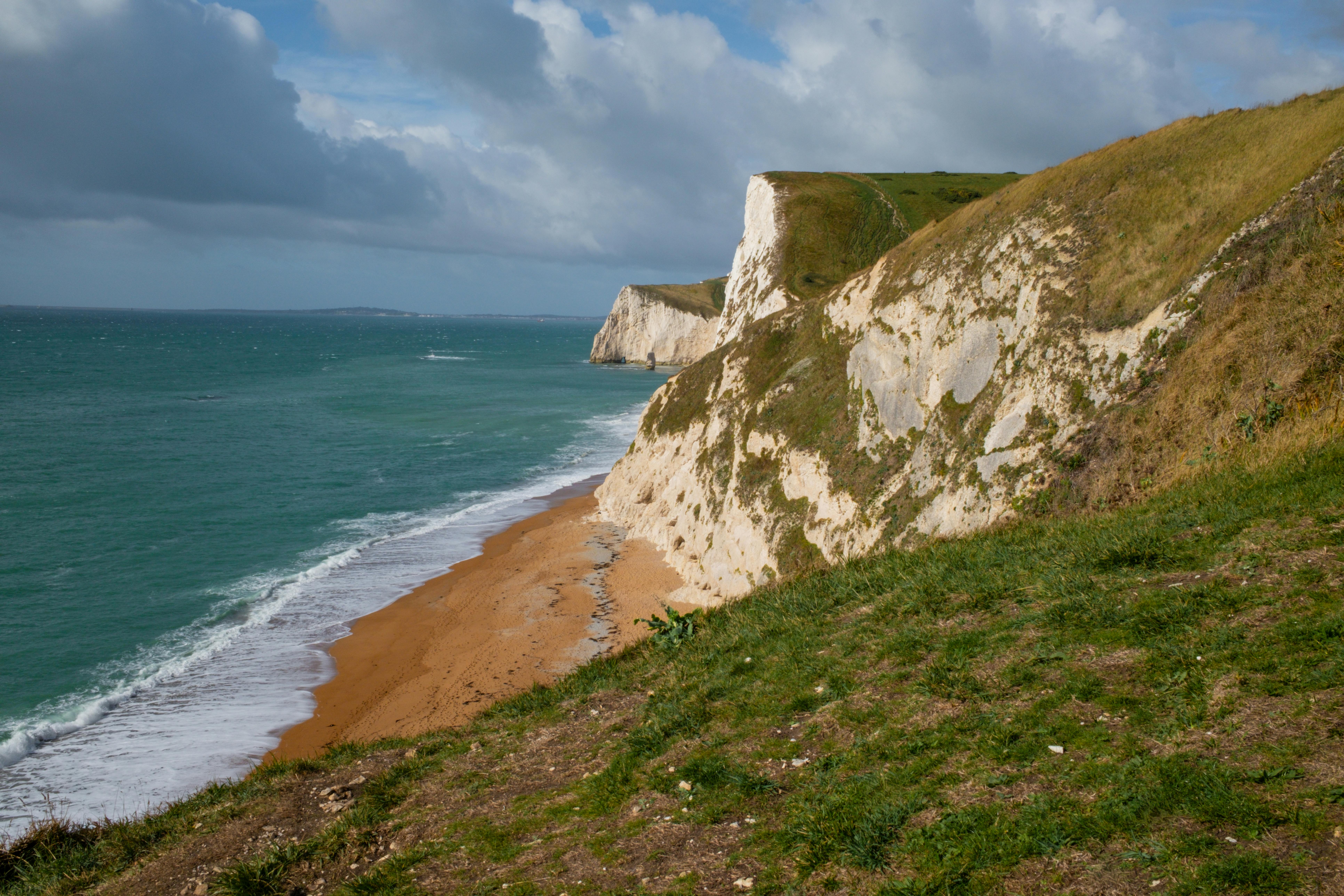 英格兰的侏罗纪海岸，拥有标志性的悬崖和戏剧性的景观，碧绿的大海与沙滩相映成趣