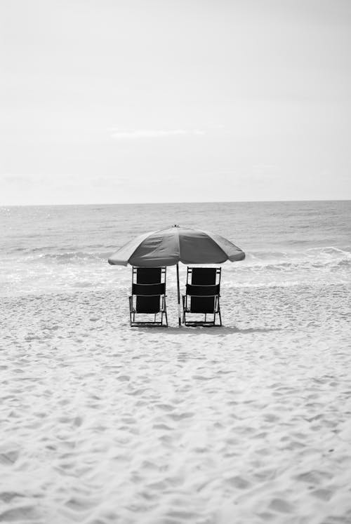 Grayscale Photography of Two Armchairs Near Body of Water