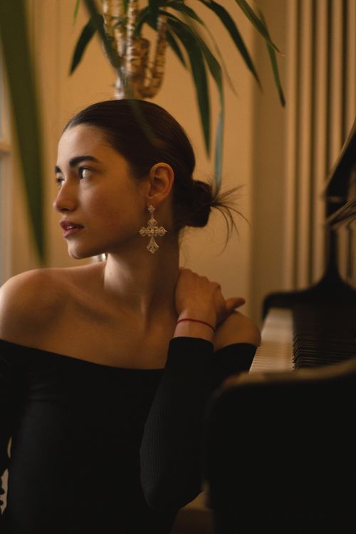 Free Elegant woman in black dress beside piano, exuding sophistication in warm, soft light. Stock Photo
