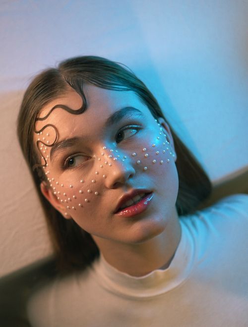 Free A woman with artistic pearl makeup under soft, colorful lighting. Stock Photo