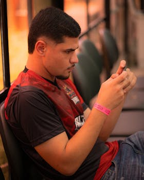 Young adult focused on smartphone gaming in an indoor setting, showcasing concentration and digital engagement.