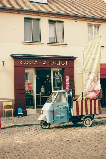 Quaint gelato shop with a colorful cart on a cobblestone street in Germany.